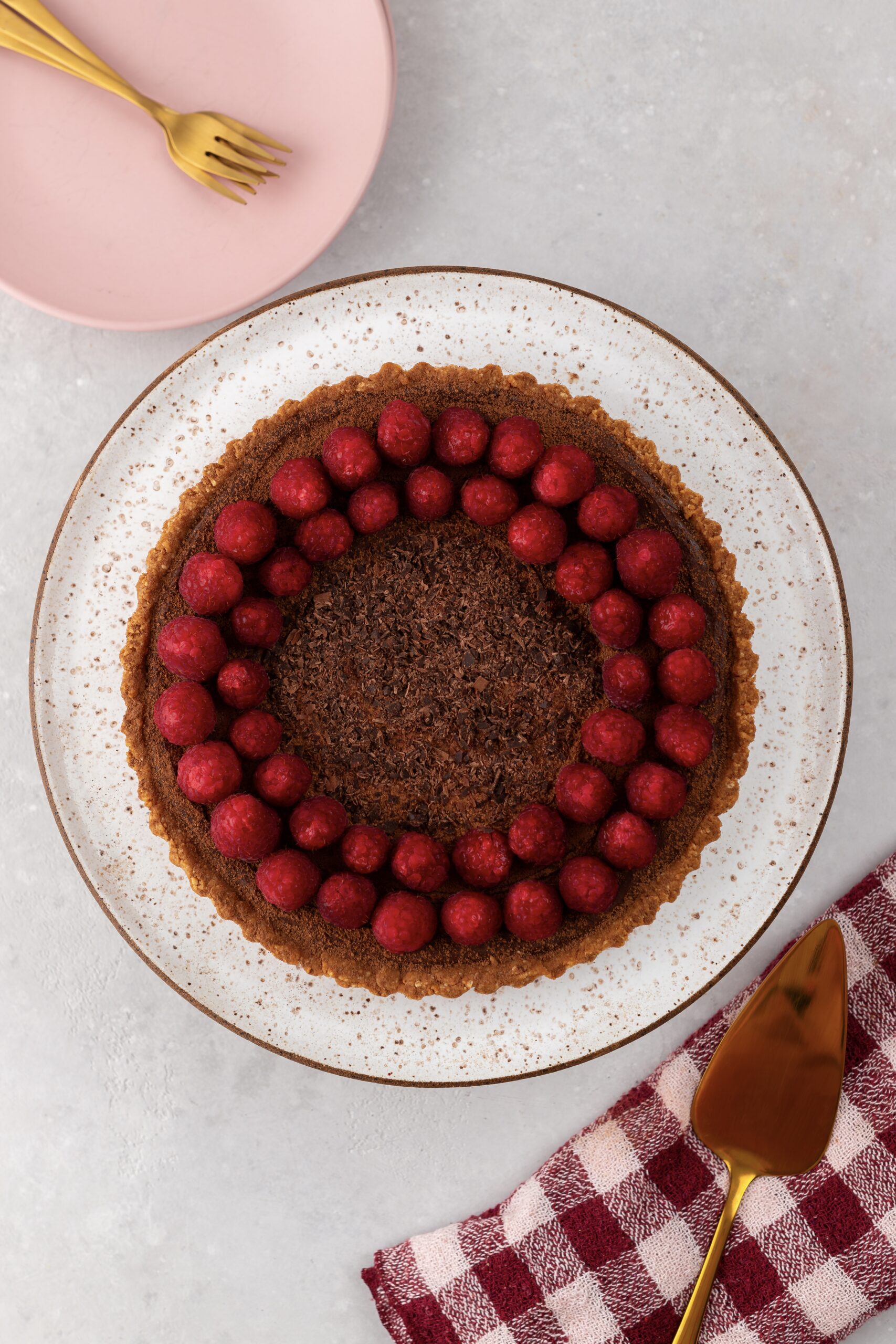 torta franuí vegana decorada com ganache de chocolate, raspas de chocolate e framboesas frescas